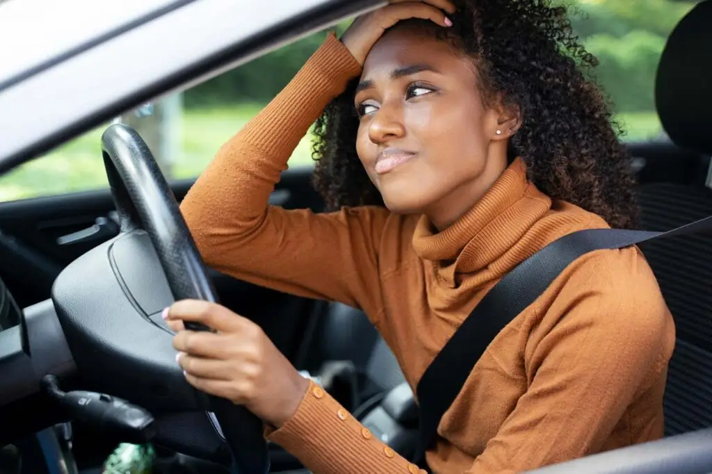 Woman with hand on head in a car accident